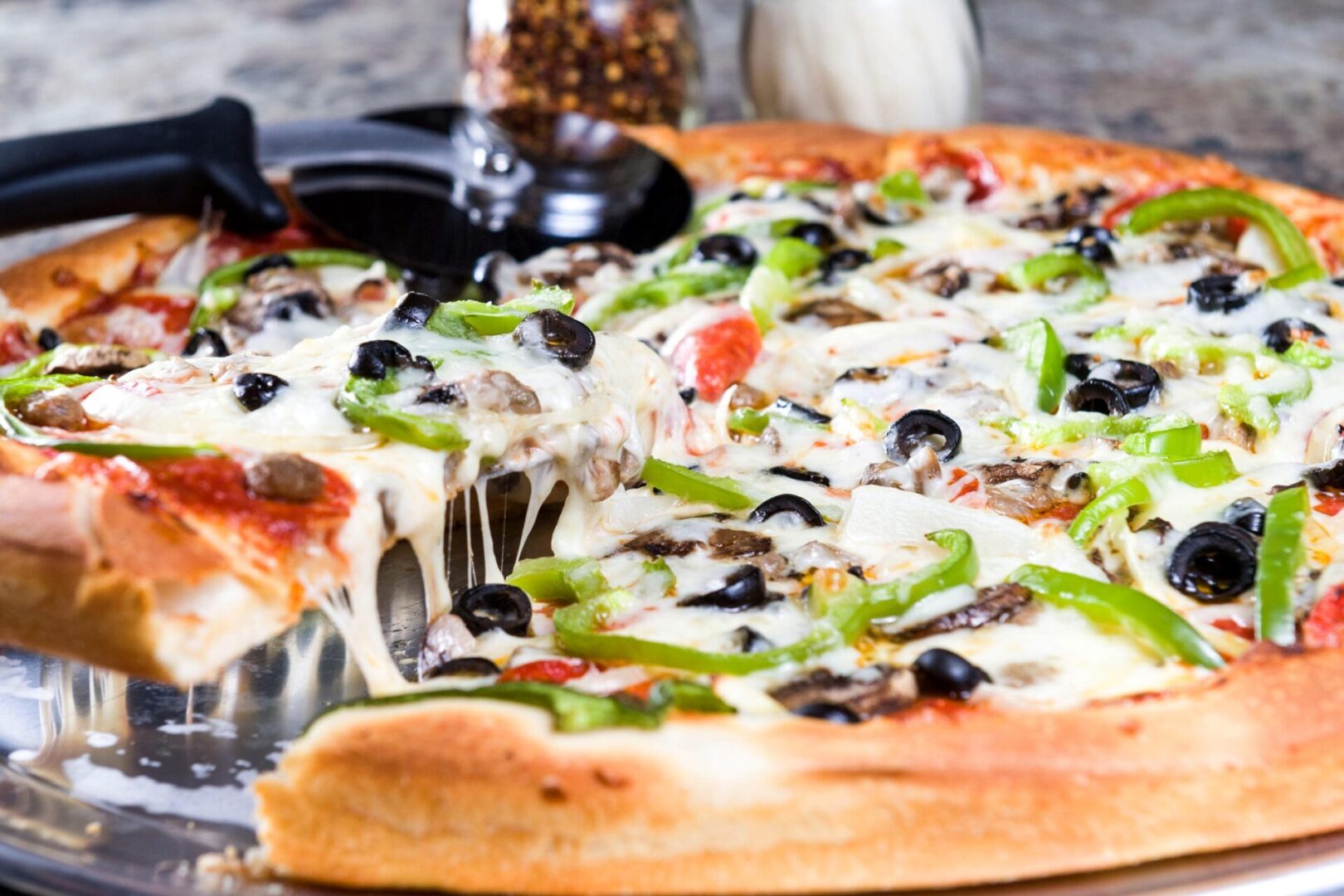 A pizza with olives, mushrooms and peppers on it.